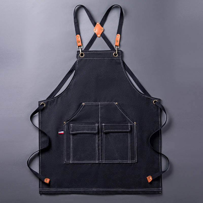 WorkEase black canvas apron laid flat, showing the crossback straps and four front pockets