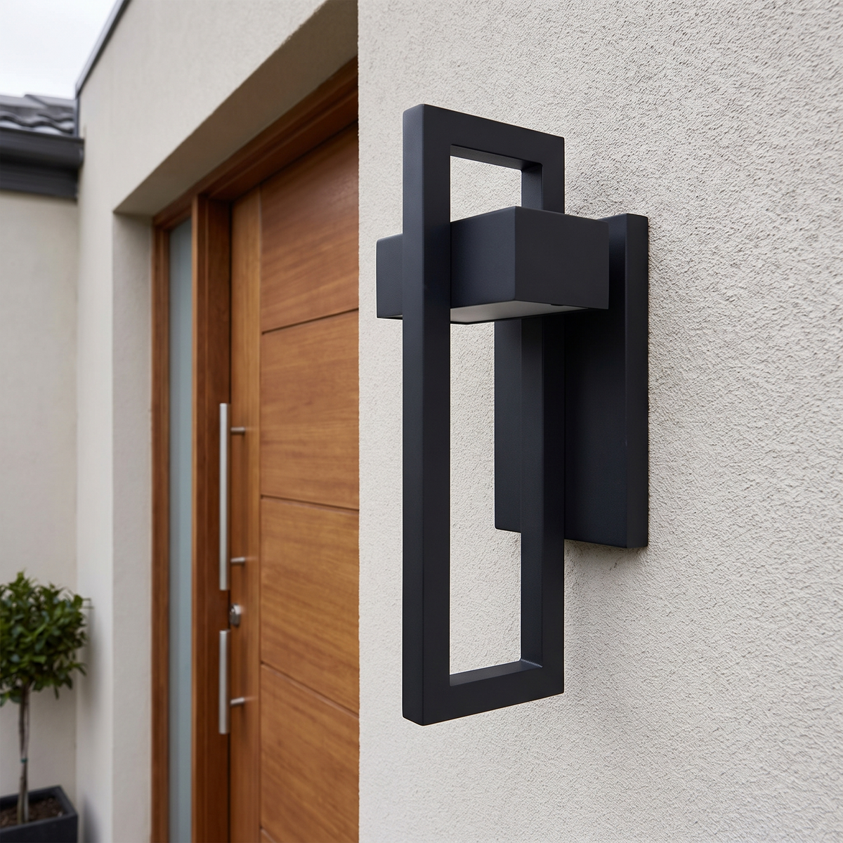 Norra framed outdoor wall lamp mounted flat against a rendered wall in daylight
