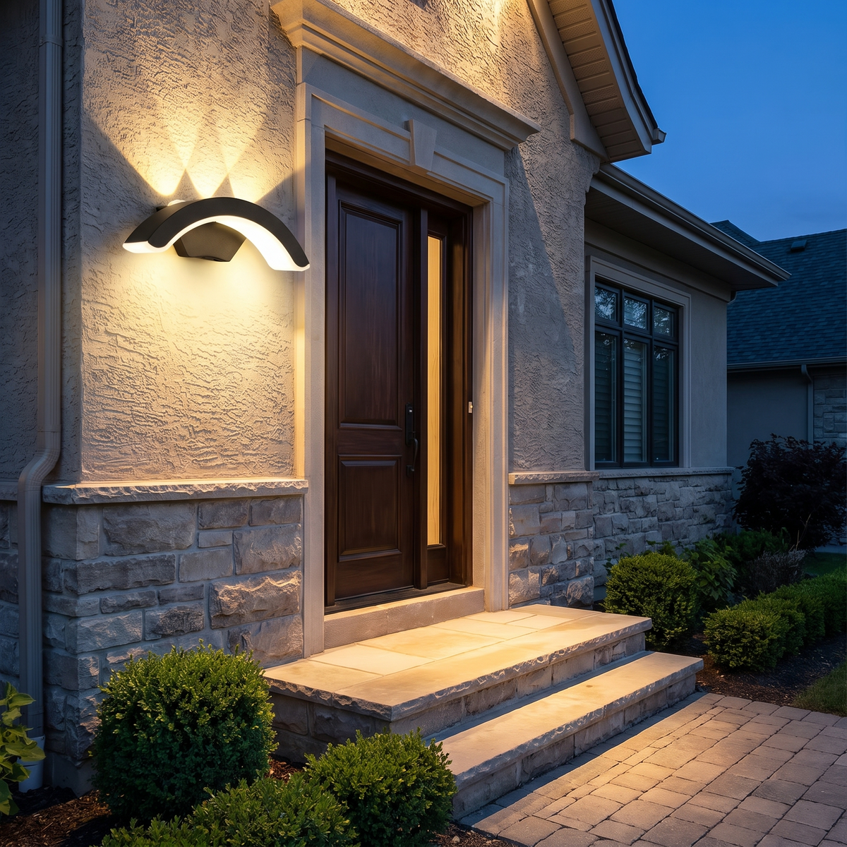 StormLite wall light lit at dusk beside a door, light spreading up the wall and over the step