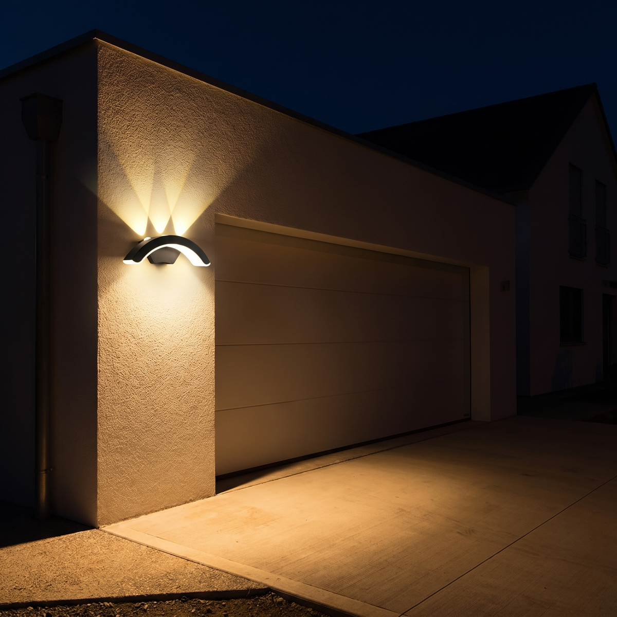 StormLite wall light lit at night, washing light up the wall and over the driveway